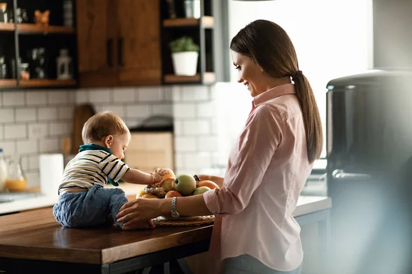 Smiling Mother Her Baby Son Who Playing Fruit Kitchen Counter — Fotografia de Stock