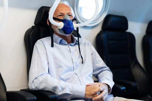 Mature patient breathing through oxygen mask during therapy in hyperbaric chamber at clinic. 