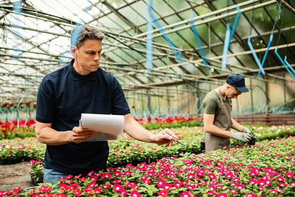 Mid Adult Man Going List Flowers While Working Garden Center — Fotografia de Stock