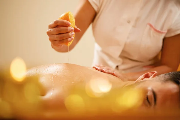 Close Therapist Using Orange Juice While Massaging Man Back Spa — 图库照片