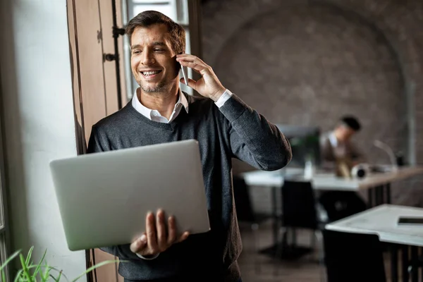 Smiling Businessman Standing Window Office Communicating Cell Phone While Holding — Stock Fotó