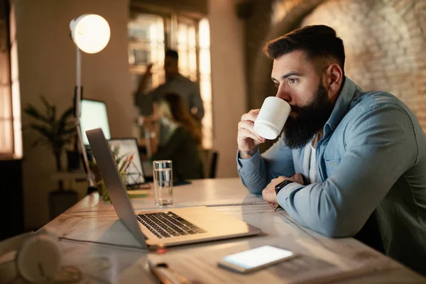 Young Businessman Surfing Net Computer While Drinking Coffee Evening Office — Foto de Stock