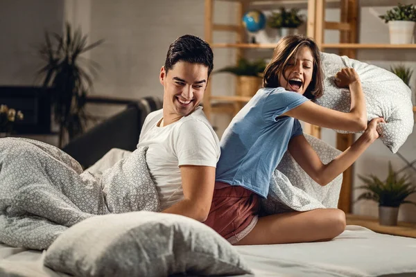 Young happy couple having fun during a pillow fight in the bedroom. 