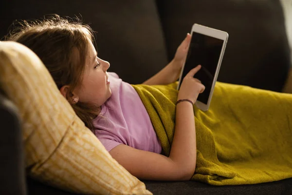 Small Girl Lying Sofa Surfing Net Digital Tablet Home — Stockfoto