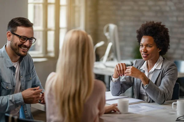 Black female insurance agent communicating with a couple during the meeting in the office. 