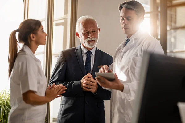 Mid Adult Doctor Senior Businessman Reading Data Touchpad Clinic — Fotografia de Stock