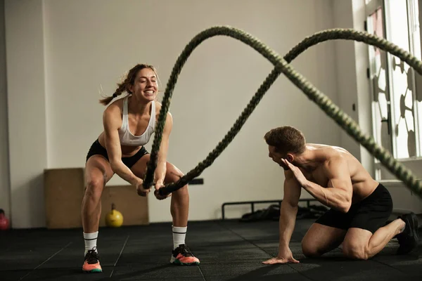 Dedicated Sportswoman Exercising Battle Rope While Coach Encouraging Her Cross — Stockfoto