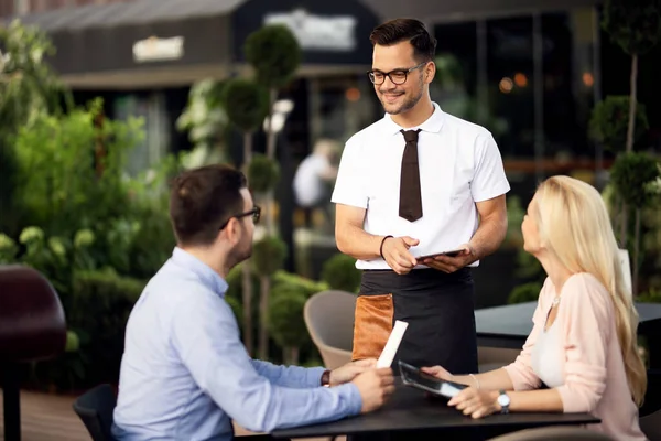 Young Smiling Waiter Communicating Guests While Serving Them Restaurant — Stockfoto