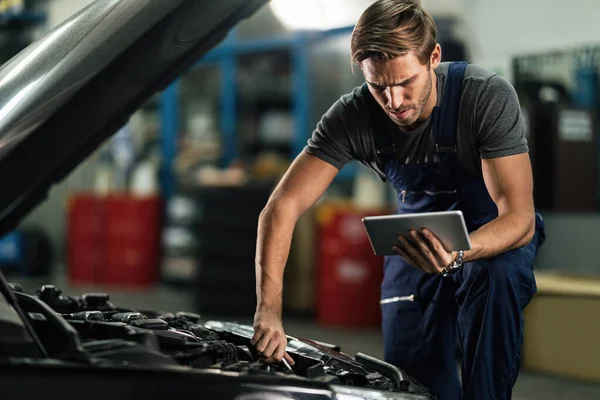 Young Auto Repairman Working Car Engine While Using Digital Tablet — Stock fotografie