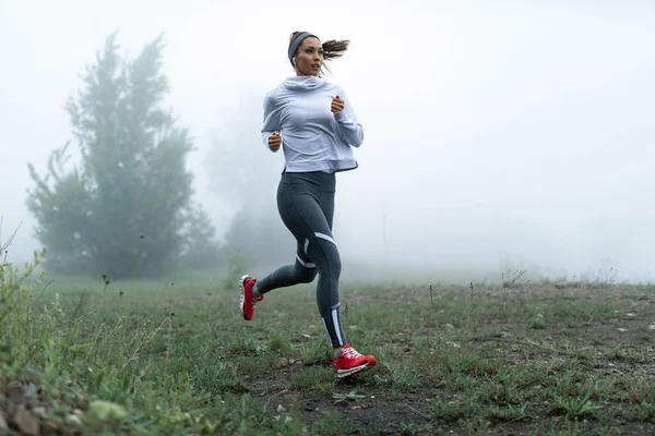 Determined Female Runner Jogging Misty Filed Morning Copy Space — Fotografia de Stock