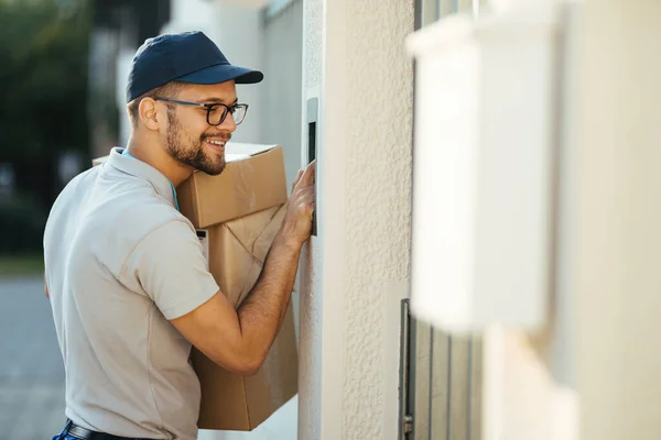 Young Happy Deliverer Packages Ringing Intercom Gate House — Stockfoto