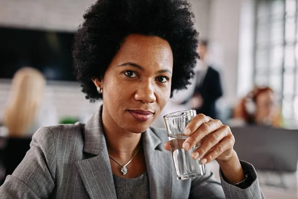 Smiling Black Businesswoman Drinking Water Looking Camera While Being Work — Φωτογραφία Αρχείου
