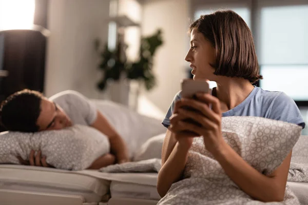 Unfaithful Woman Using Cell Phone Cheating Her Boyfriend Who Sleeping — Foto de Stock