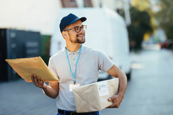 Young Smiling Postal Worker Walking Residential District While Making Delivery — Stockfoto