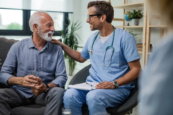 Happy Doctor Talking Senior Male Patient While Being Home Visit — Fotografia de Stock