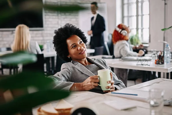 Χαμογελώντας Αφρο Αμερικανίδα Επιχειρηματίας Πίνει Καφέ Στο Γραφείο Της Και — Φωτογραφία Αρχείου