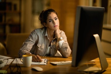 Young woman feeling exhausted working late on a computer at home. 