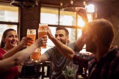 Group of happy young people toasting with beer and having fun in a pub. 