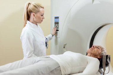 Female doctor a patient during CT scan procedure in the hospital. 