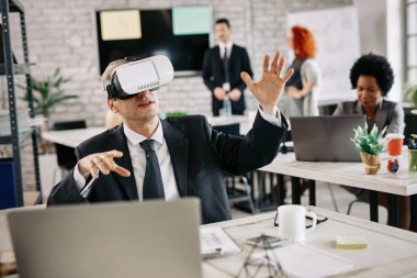Mid adult businessman trying out virtual reality simulator while taking a break from work in the office. 