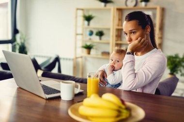 Young woman with baby experiencing postpartum depression and contemplating at home. 