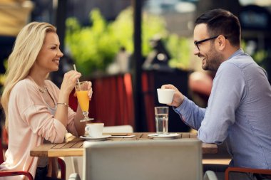 Happy couple enjoying in a cafe and talking to each other. Focus is on man. 