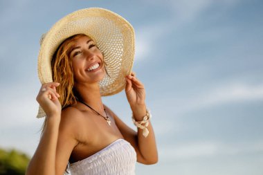Young beautiful woman having fun on a summer day while reaching out for someone on the beach.