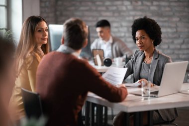 Couple communicating while having a meeting with their financial advisor in the office. Focus is on financial advisor. 