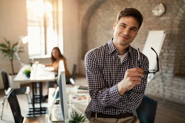 Portrait of happy confident businessman looking at camera while being in the office. 