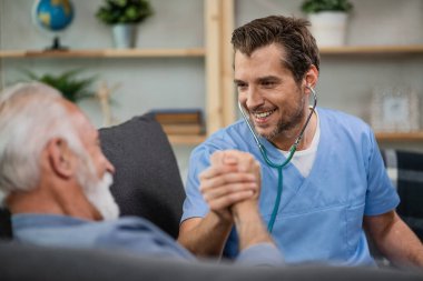 Happy healthcare worker greeting his mature patient while being in a home visit. 