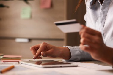 Close up of woman using digital tablet while buying on the Internet with credit card. 