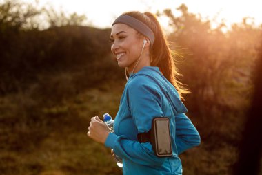 Young happy athletic woman running in nature in the morning. 