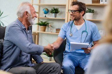 Happy general practitioner greeting with senior man while being in a home visit. 