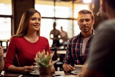 Young couple drinking coffee and enjoying while talking with their friends during coffee time in a cafe. 