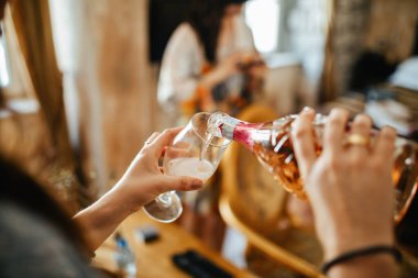 Close up of unrecognizable woman filling glass with Champagne. 