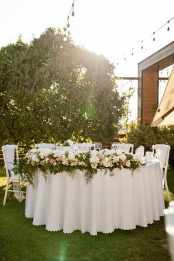 Elegant table setting with flower arrangement at outdoor wedding reception. 