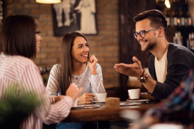 Group of happy friends drinking coffee and talking in coffee ship.