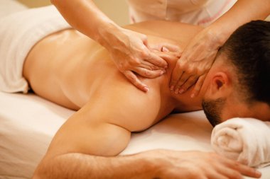 Close-up of therapist pinching man's shoulders during back massage at  the spa. 