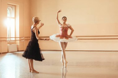Smiling ballerina having ballet class with her teacher in dance studio. Copy space. 