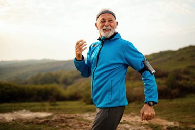 Happy senior runner jogging in nature and enjoying in healthy lifestyle. 