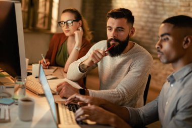 Genç iş adamı ve Afrikalı Amerikalı meslektaşı geç saatlere kadar dizüstü bilgisayarla çalışıyorlar.. 