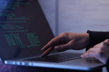 Close up of unrecognizable computer hacker stealing computer software while using laptop.
