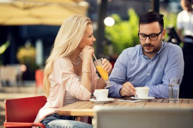 Mid adult couple relaxing in a cafe and talking to each other. 