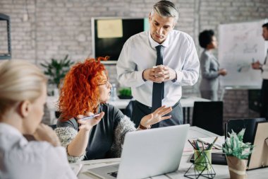 Young businesswoman explaining something to her colleagues on a meeting in the office. 
