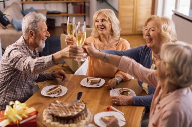 Happy senior people having fun while celebrating Birthday and toasting with Champagne.
