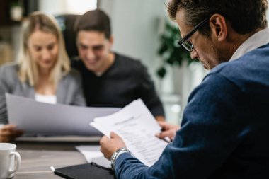 Financial advisor having consultations with a couple and analyzing their financial reports. 
