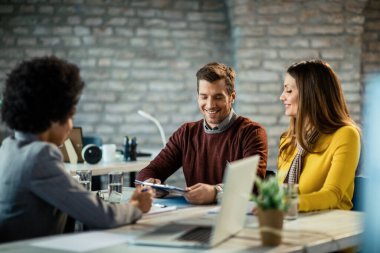Happy mid adult couple having a meeting with their insurance agent. Focus is on man.