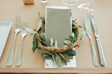 Close up of wedding table setting decorated with eucalyptus flower wreath. 