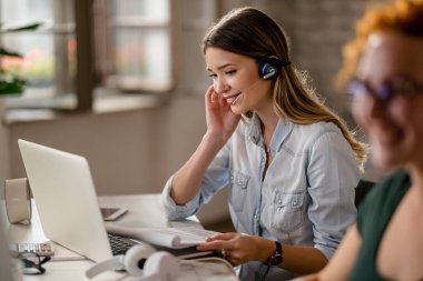 Smiling customer service operator with headset talking with a customer while working in call center. 