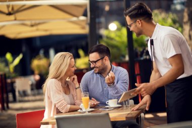 Smiling couple holding hands and communicating while deciding what to order in a restaurant. 